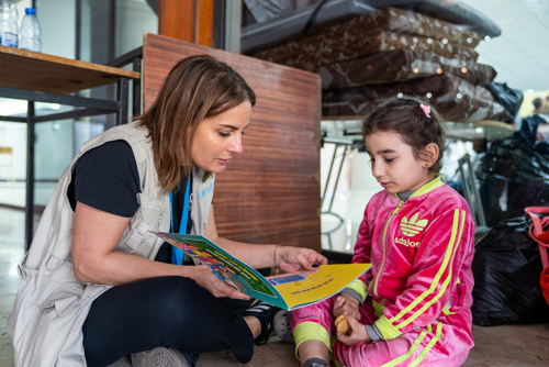 UNICEF vrijwilliger leest boek voor aan een kind